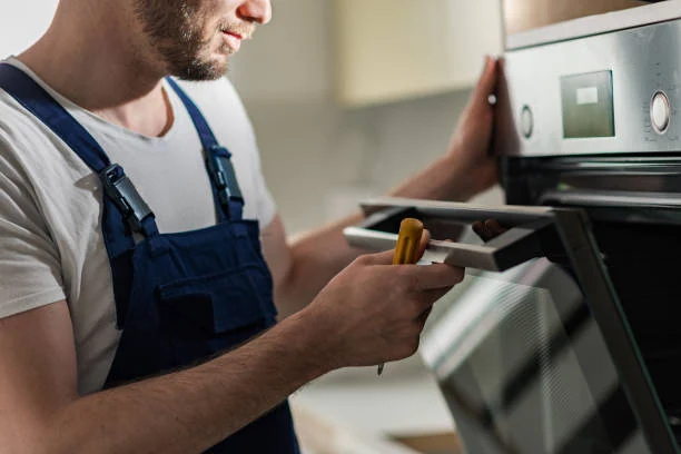 Technician inspecting the control panel of a built-in oven