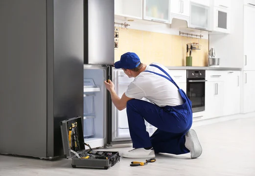 Technician working on a stainless steel refrigerator in a home kitchen
