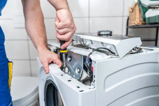 Close-up of a technician working on washing machine controls